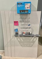 Four white peg boards with a 43-piece pegboard organizer kit, metal hooks, a shelf attachment, and mounting hardware displayed on and around the peg boards.