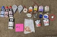Photo of plumbing supplies including putty, pipe sealing tape, cement, primer, solder, flux, chalk line reels, copper fittings, and pipe cutter parts.