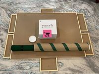 Photo of a large beige felt puzzle tray with six sliding drawers around the edges, a box of Puzzle EZ sorting trays, a rolled-up green and tan felt puzzle keeper, and small white container on a patterned carpet.