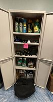 Open plastic shed interior shelves with garden products, tools, and planter bags at bottom