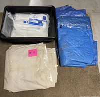 Photo of blue plastic tarp, white plastic sheets inside black tub, and folded heavy canvas drop cloth