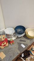 Collection displayed on stone surface including Avon Ted E. Bears, mixing bowls, casserole dishes, and glass juicer.