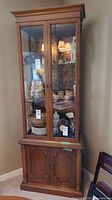 Full front view of the wood display cabinet showing two glass doors with visible shelves inside and lower cupboard section.