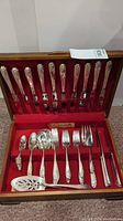 Full set of Rogers Bros Daffodil collection silverware in a wooden canteen box with red velvet lining, showing knives, forks, spoons, sugar tongs, and serving utensils.