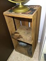 Wooden fruit crate with visible wear and old sad iron on bottom shelf, globe on top.