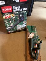 Photo of boxed Toro electric Super Blower Vac alongside boxed Black & Decker 13 inch electric hedge trimmer, both on floor, untested condition noted.