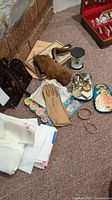 Full view of lot contents including linens, gloves, brush set, tins, jewelry, bracelets, watch, and spoons