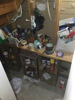 Photo of wooden shelving with various paint cans, rollers, tapes, cords, and other small tools