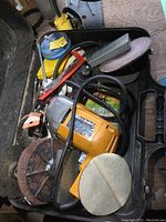 Various power tools and sanding/polishing attachments inside a black case including Black and Decker circular saw, rotary tool, and jigsaw