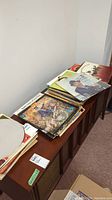 Two stacks of vinyl LP records on wooden cabinet under overhead lighting
