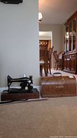 Vintage Singer sewing machine on wooden base with curved wooden carrying case beside it
