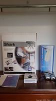 Full lot on tabletop showing Shark steam cleaner box, shredder box, manual, and walkie talkies