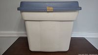 Photo showing the full 22 gallon Rubbermaid storage bin with white base and blue lid on a wooden surface.