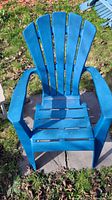 Photo of one blue plastic Adirondack chair showing the front with wide armrests, slatted back and seat.