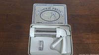 Cookie press tool and disks in storage tray inside box labeled Cookie Press.