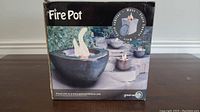 Photo of boxed ceramic fire pot showing front label with image of pot in use outdoors.