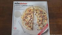 Box front showing the thinkkitchen 13-inch Tivoli pizza stone with a pizza image and product details.