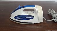Side view of Panasonic white and blue steam iron showing brand and model number NI-305M
