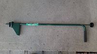 Full weed remover tool showing green metal shaft with handle and prong end