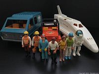 Front view of seven Adventure People figures lined up with three vehicles behind them: blue camper van, orange jeep, and white space shuttle with astronaut figure standing in front.