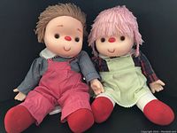 Pair of 1980s Ice Cream Dolls sitting side by side against black background, showing front view and holding hands.