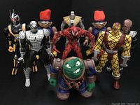 Group photo of 9 assorted 1990s action figures including characters from Spider-Man, Bucky O'Hare, Star Trek, Stone Protectors, and Mummies Alive lined up against a black background.