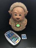 Front view of the doll with accessories showing the electronic control panel and story cartridge.