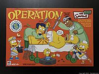 Photo of the front of the closed game box showing The Simpsons themed Operation game design artwork and branding.