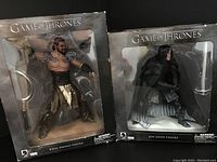Both Khal Drogo and Jon Snow figures sealed in their original window boxes with visible box wear.