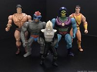 Full group shot of the five 70s-80s action figures including He-Man style barbarian, bird humanoid, Cylon Centurion, Skeletor from MOTU, and young male Titan figure.
