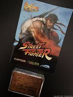 Photo showing the front of the instruction manual with Ryu artwork and the brown case containing the card deck.