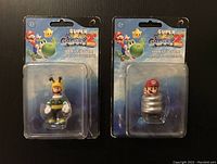 Photo showing both Super Mario Galaxy 2 mini figures (Mario and Luigi) sealed on cardbacks, with visible wear on the cardbacks.