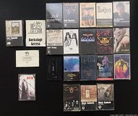 Photo showing 18 cassette tapes and cases from various classic rock artists including Led Zeppelin, The Beatles, Jimi Hendrix, Aerosmith, Queen, Neil Young, Pearl Jam, Black Sabbath, Pink Floyd, Ozzy Osbourne, John Lennon, Robert Plant. Includes 3 empty cases and 1 loose cassette tape.