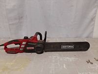 Side view of the red and black Craftsman electric chainsaw showing the bar, handle, and body.