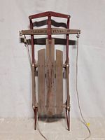 Full view of Flexible Flyer III sled showing wooden slats, red metal frame, and steering rope.
