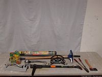 Wide view showing all gardening tools and equipment spread on table against white backdrop.