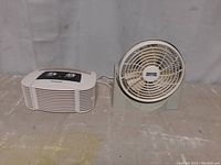 Both Honeywell air purifier and Lasko fan side by side on surface