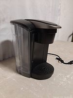 Side view showing black and silver Keurig K-Select unit with clear water reservoir attached.
