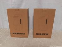 Two cardboard boxes labeled 'DEHUMIDIFIER' containing the dehumidifiers.