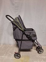 Side view of the gray pet carriage with canopy and storage basket underneath, showing frame and wheels