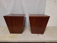 Two wooden storage trunks side by side, showing tapered square shape and dark wood finish.