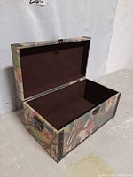 Photo showing open view of the chest from the side, highlighting interior lined in brown fabric, metal clasp on front, floral exterior fabric.