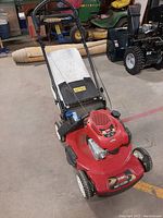 Front angle view showing the red Toro mower with white rear grass bag and handlebar controls.