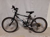 Side view of black Trek Mountain Lion children's mountain bike showing right side with drivetrain, gears, and seatpost suspension.