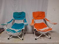 Two folding beach chairs, one teal and white, one orange and white, shown side by side.