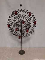 Full front view of the wrought iron candle holder sculpture with red glass holders showing the spiral leaf design and base.