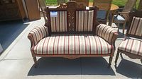 Full front view showing carved crest, upholstered back, seat, and arms.