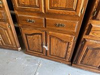 Full view of oak wood entertainment center showing drawers, doors and wood grain.
