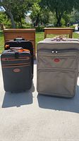 Front view of two luggage pieces, one black and one gray, showing fabric exteriors with visible wear and stains.