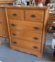 Front view of the Mid Century Modern wood chest of drawers showing five drawers with metal handles and wood finish.